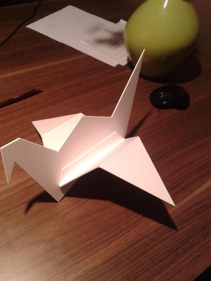 Papierowy żuraw origami z białego kartonu na biurku – prototyp dekoracji salonu